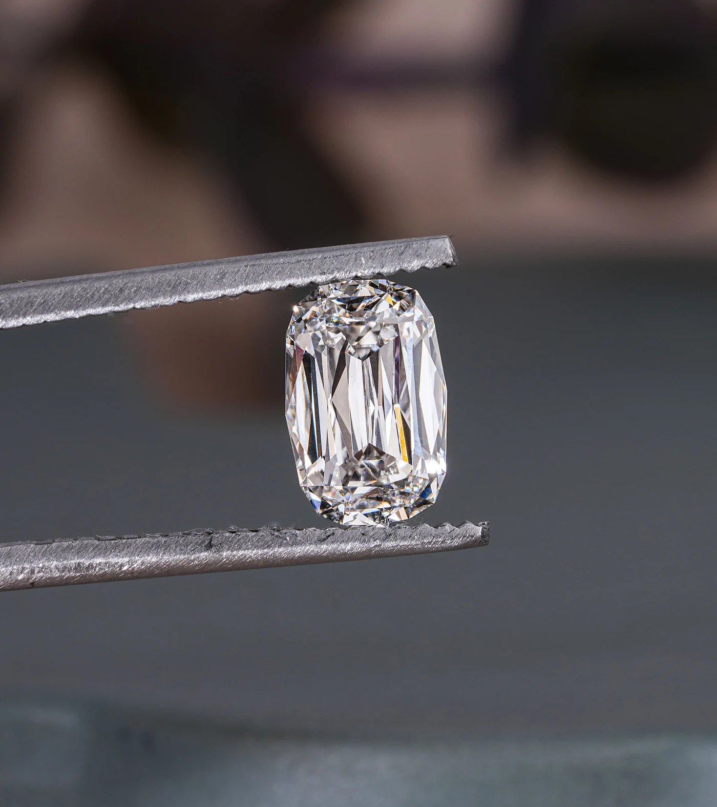 Diamant de forme allongée tenu dans une pince sur fond gris